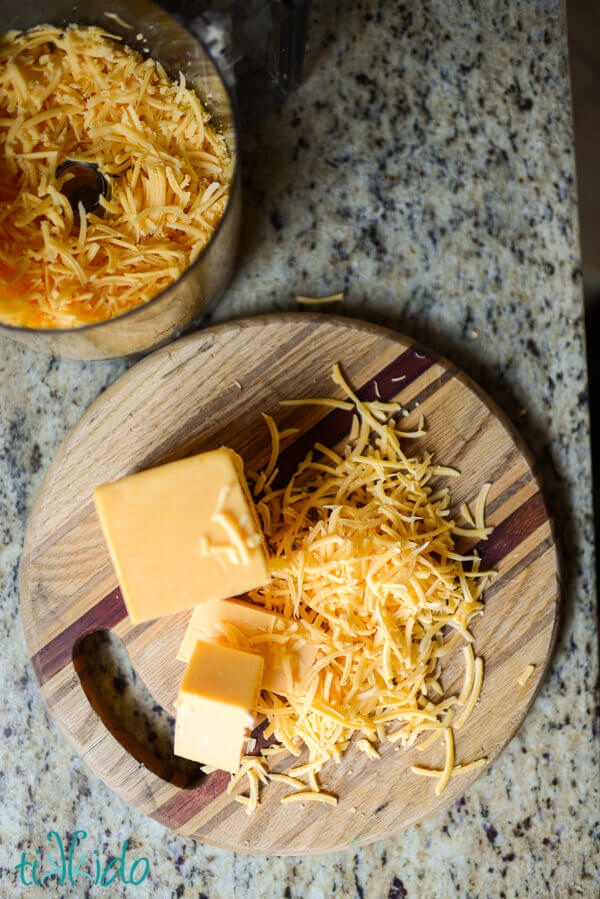 Block of cheese partially shredded on a wooden cutting board for making Cheese crackers.