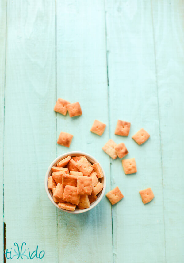 Homemade cheese crackers in a bowl on an aqua wooden background.