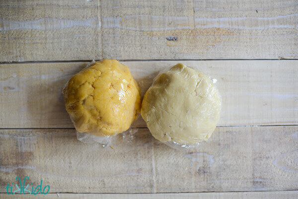 Two balls of homemade cheese cracker dough on a wooden surface.