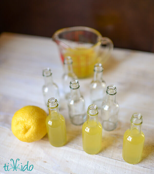 Homemade limoncello being bottled in miniature, individual serving size bottles.
