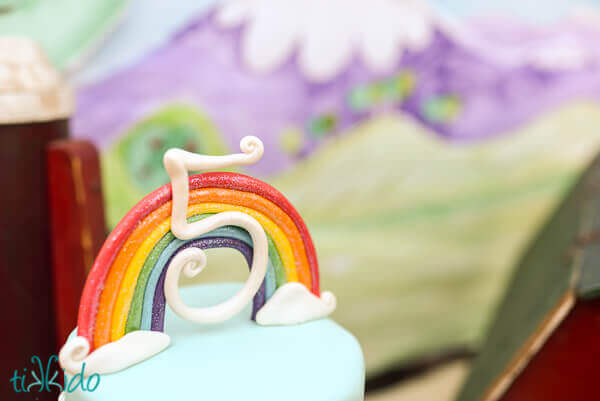 Rainbow cake topper on a blue cake.