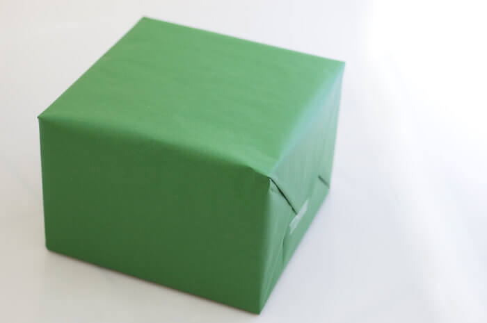 Box wrapped in plain green paper on a white background.