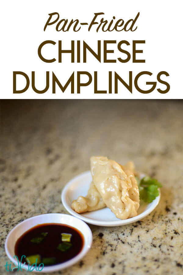 Two Chinese dumplings on a small white plate next to a small dish of soy sauce.