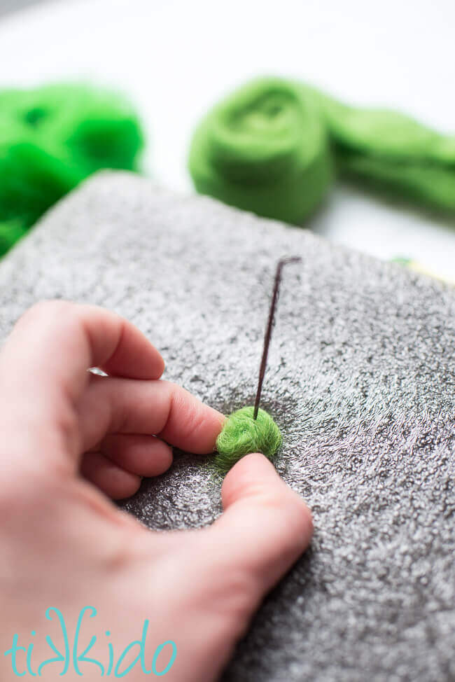 Needle felting green wool roving to make a felt ball.