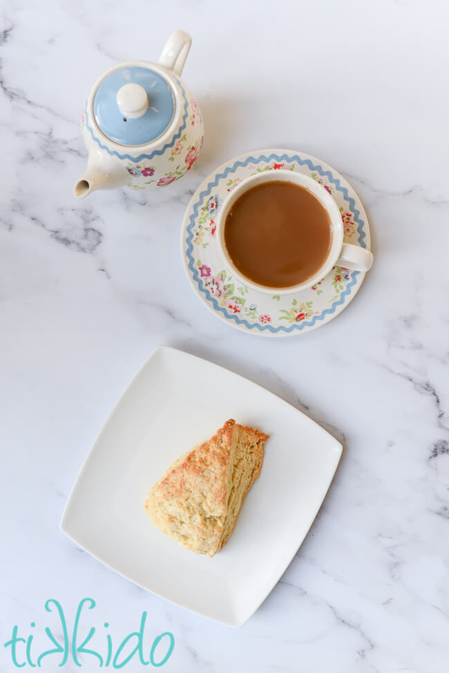 Easy Scones Recipe Scone made with an easy scones recipe on a white plate, next to a tea pot and cup of tea.