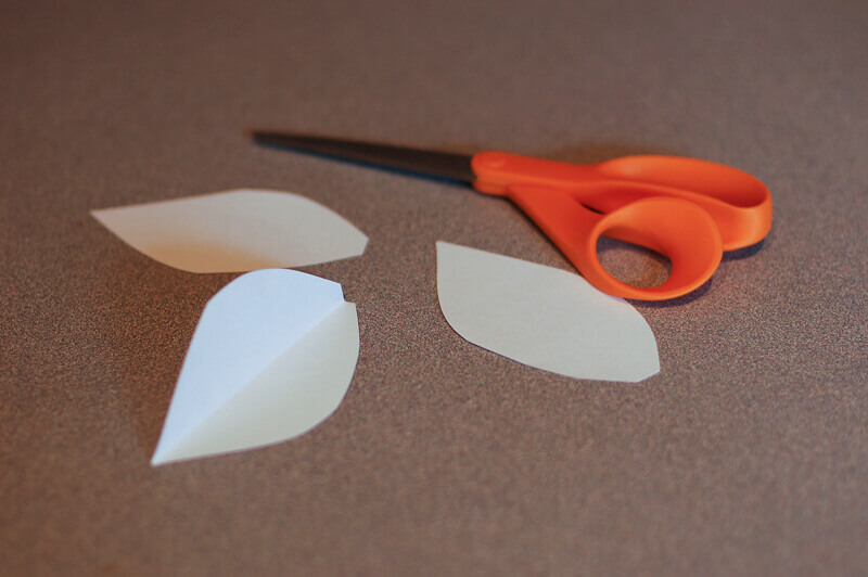 Pair of scissors and three white paper leaves.