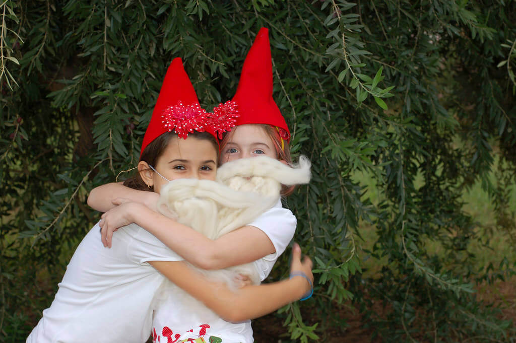 two little girls hugging and wearing gnome hats and gnome beards